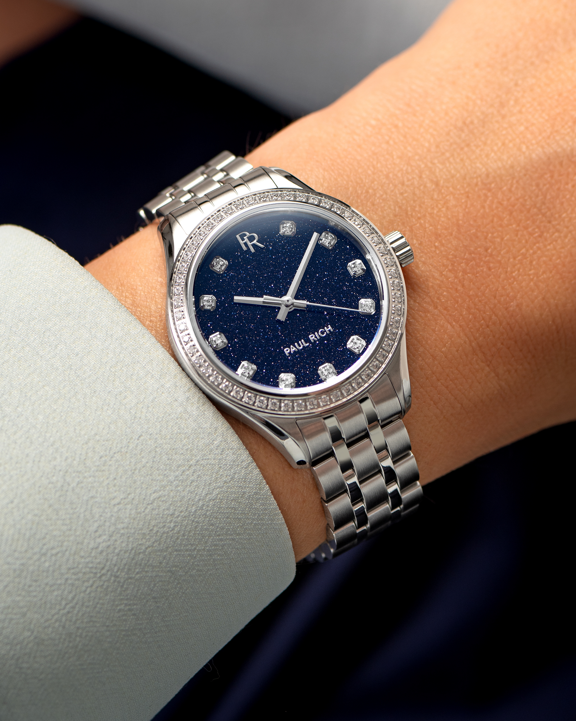 Silver watch with blue face and diamond accents on a wrist